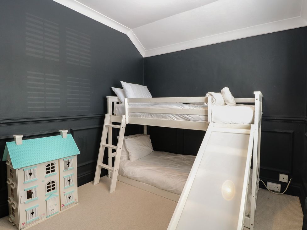 A children's bedroom with a bunk bed and dollhouse at Sunrise House in Pakefield near Lowestoft