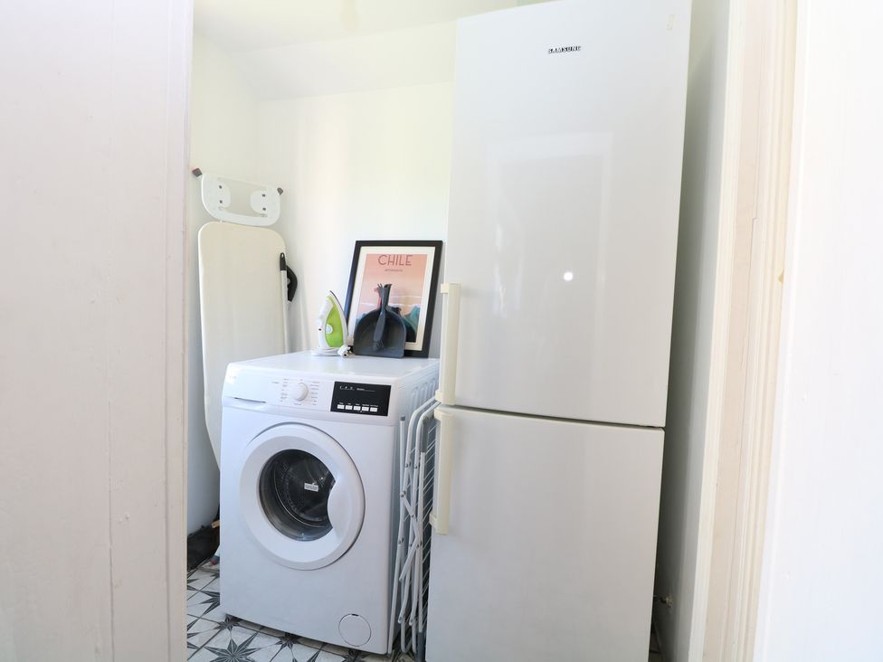 A laundry room with a washing machine and a refrigerator at Sunrise House in Pakefield near Lowestoft