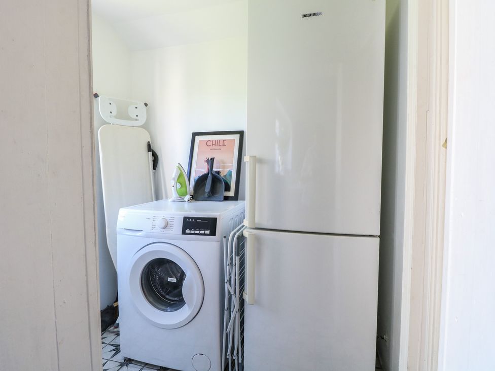 A laundry room with a washing machine and refrigerator at Sunrise House Pakefield near Lowestoft