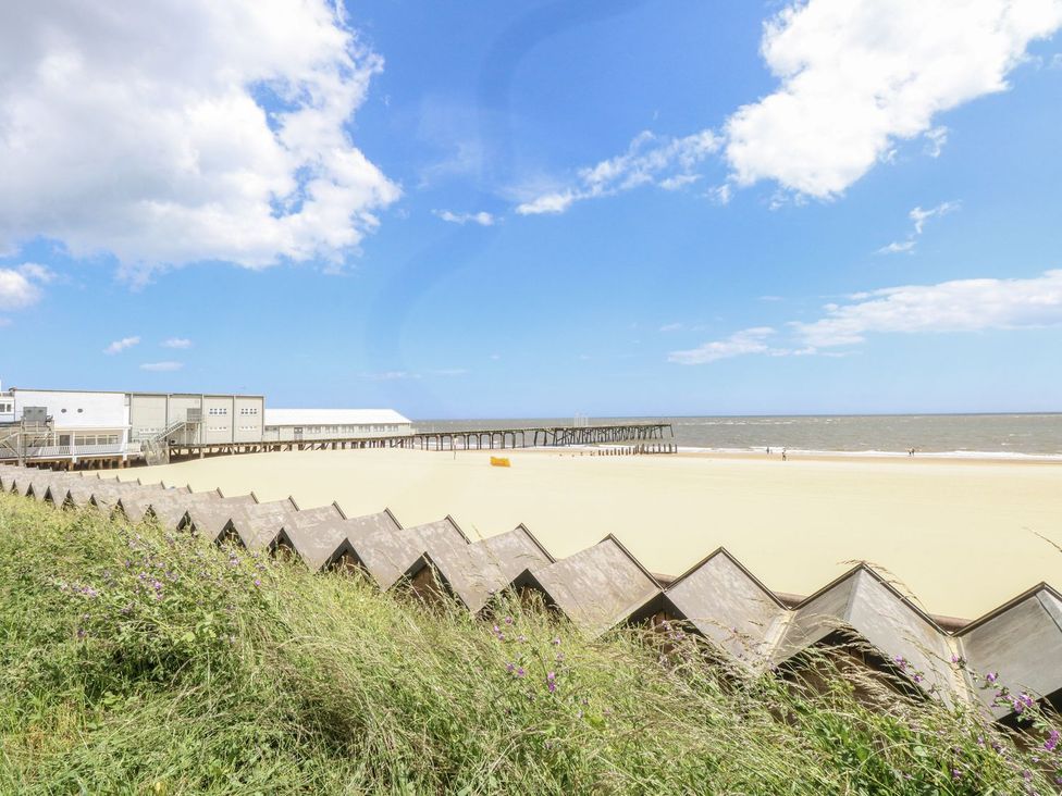 A beach with a pier and buildings at Sunrise House in Pakefield near Lowestoft