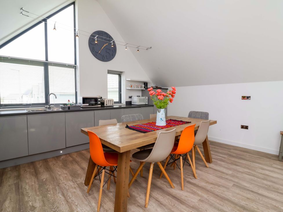 A kitchen with a dining area and flowers on the table at Pebble Ridge View in Westward Ho!
