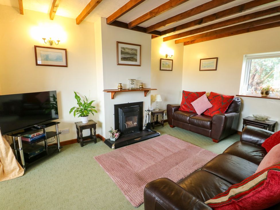 A living room with a fireplace and sofa at The Cottage at Ty Newydd in Brynsiencyn