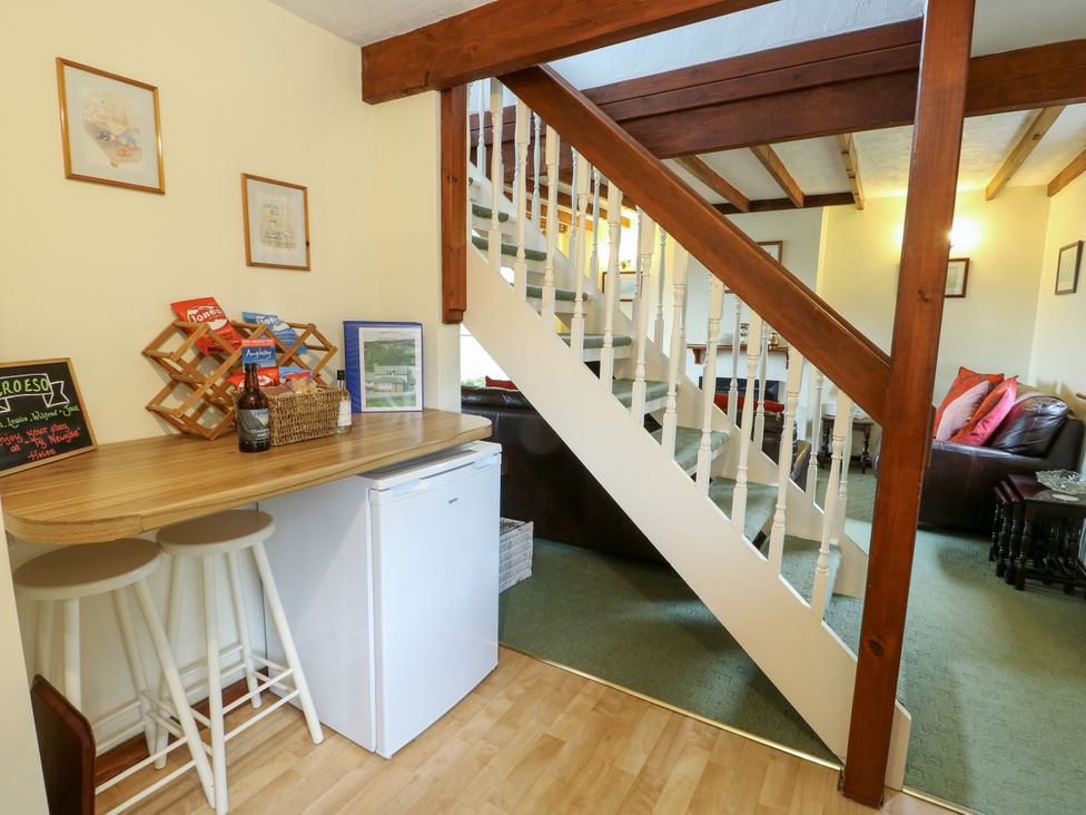 A living room with a table and stools by the stairs at The Cottage at Ty Newydd in Brynsiencyn