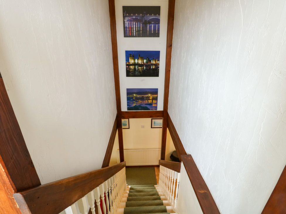 A staircase leading down with pictures on the wall at The Cottage at Ty Newydd in Brynsiencyn
