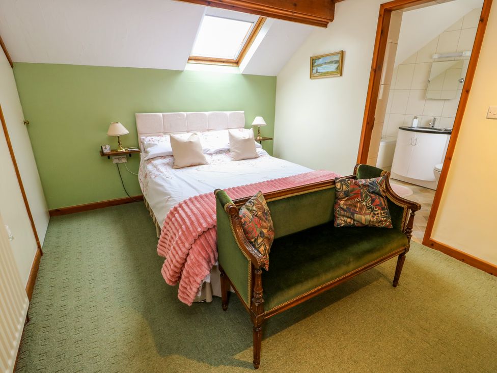 A bedroom with a bed and a couch at The Cottage at Ty Newydd in Brynsiencyn