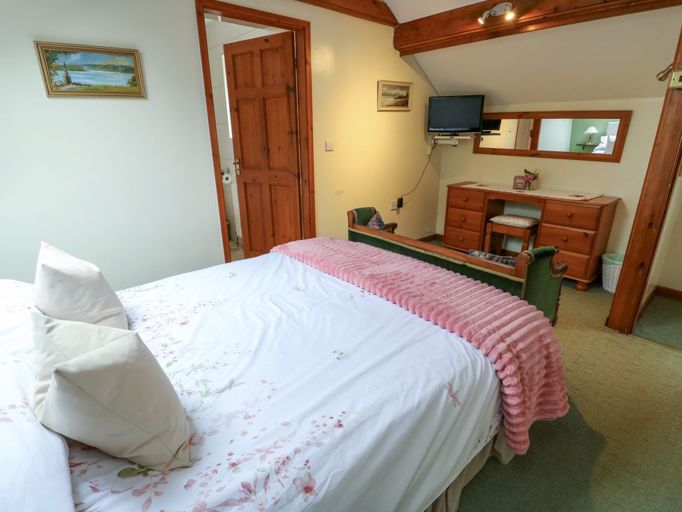 A bedroom with a bed and a dresser at The Cottage at Ty Newydd in Brynsiencyn