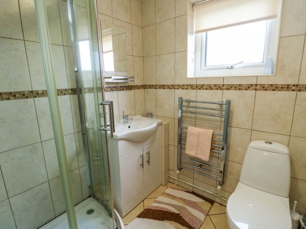 A bathroom with a shower, sink, toilet, and towel radiator at The Cottage at Ty Newydd Brynsiencyn