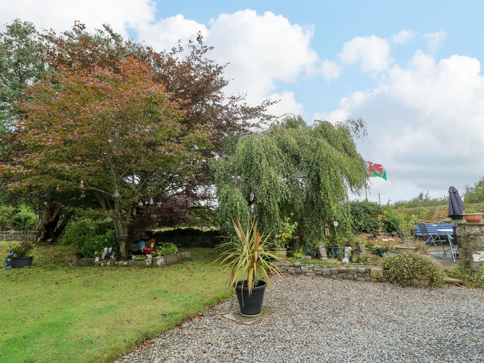 A garden with trees, a flag, and garden furniture at The Cottage at Ty Newydd Brynsiencyn