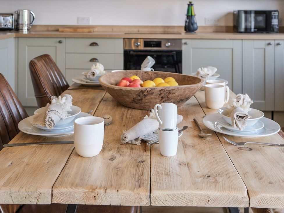 A kitchen with a wooden table and fruit bowl at Heritage Retreat in Monknash