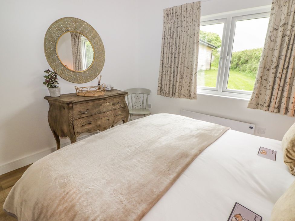 A bedroom with a bed and a wooden table at Heritage Retreat Monknash