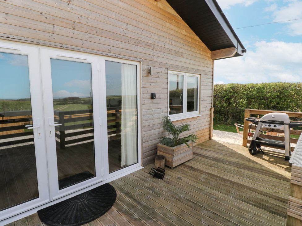 An outdoor area with a wooden deck and a barbecue grill at Heritage Retreat in Monknash