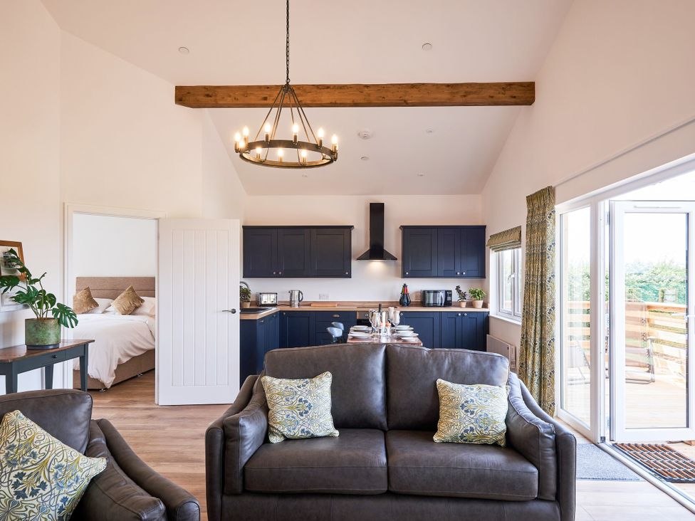 A living room with a sofa and kitchen area at Monks Rest in Monknash