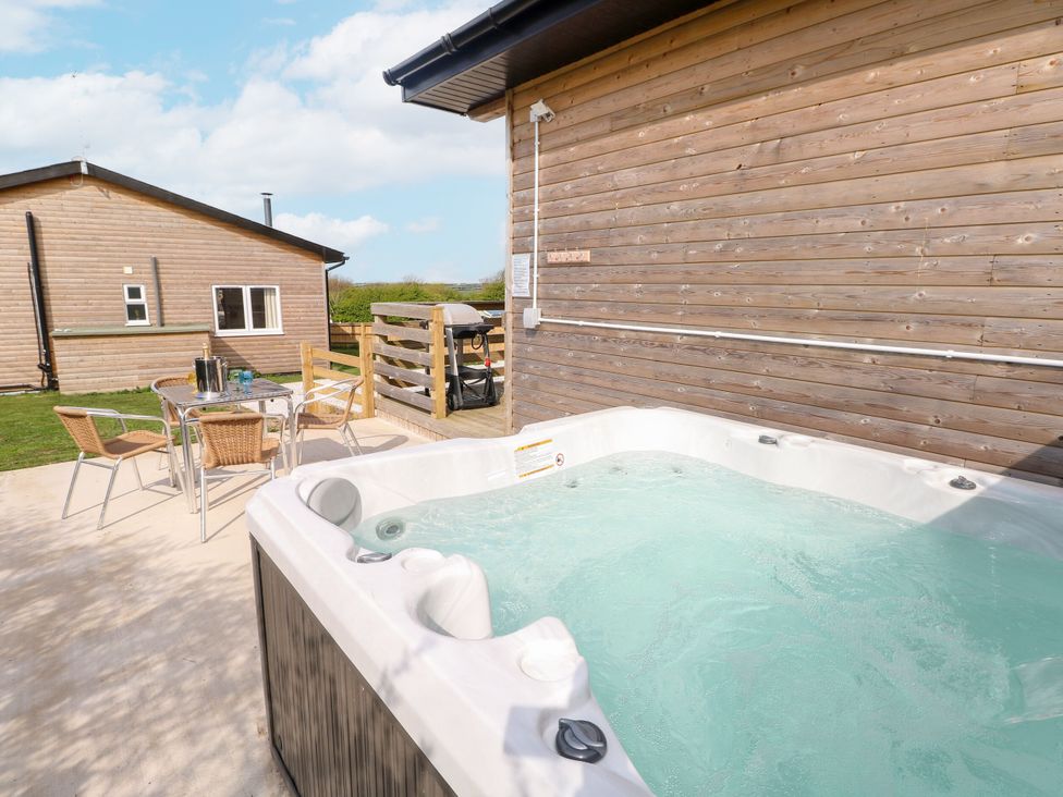 An outdoor area with a hot tub and seating at Monks Rest in Monknash