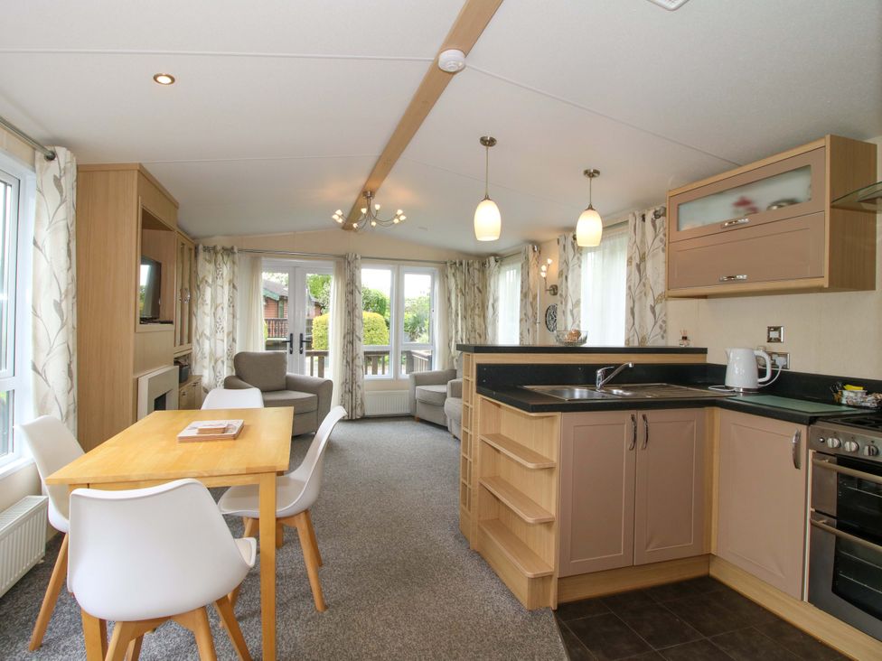 A living room with a kitchen area and dining table at Dove in Shobdon