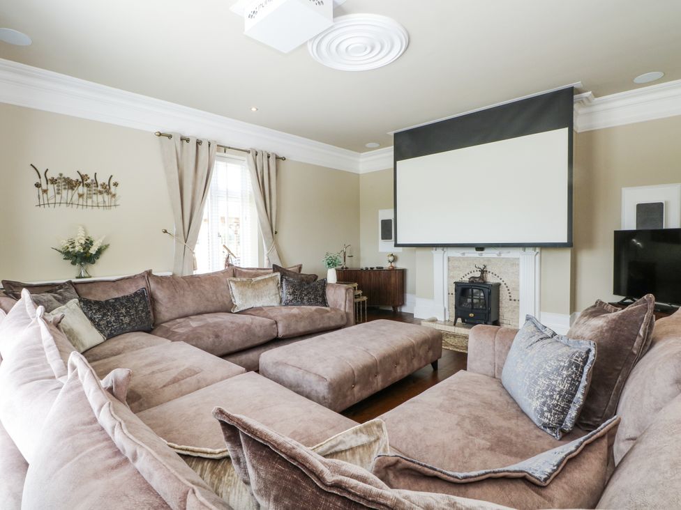 A living room with a large sofa and a projector screen at Meadow Manor And Spa in Prees near Whitchurch