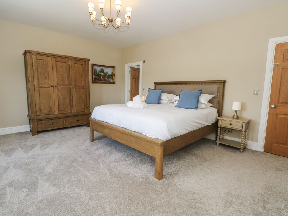 A bedroom with a bed and wardrobe at Meadow Manor And Spa Prees near Whitchurch