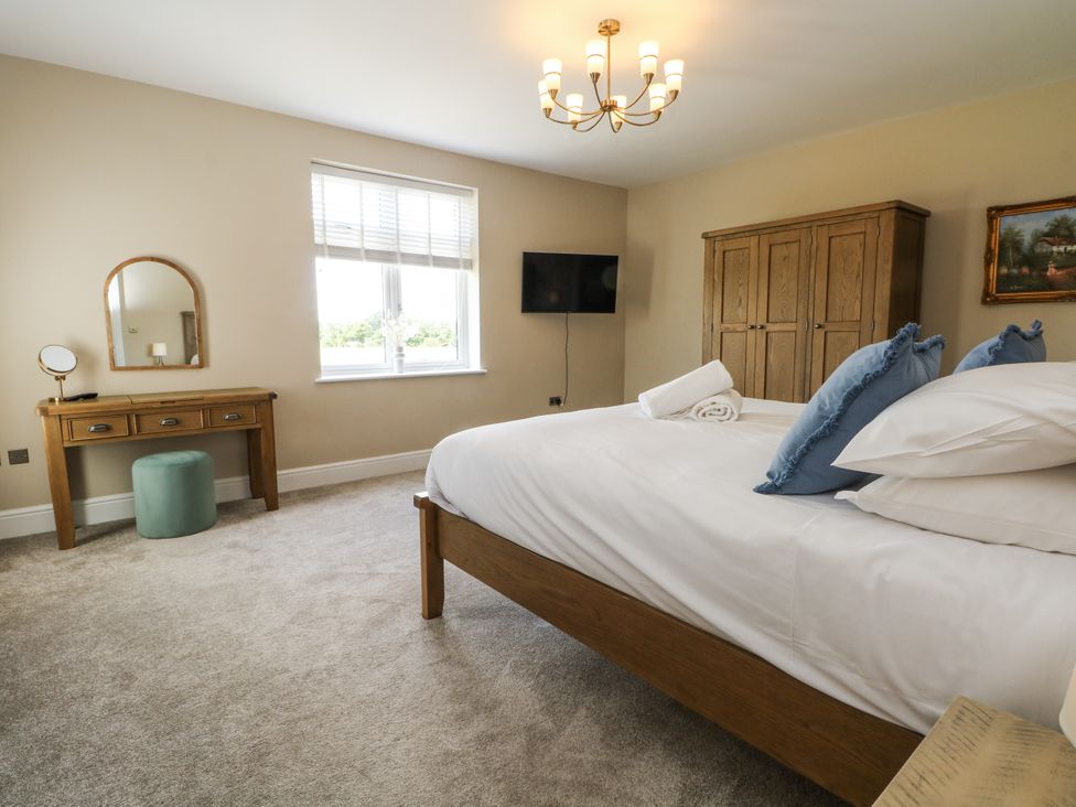 A bedroom with a bed and wardrobe at Meadow Manor And Spa Prees near Whitchurch