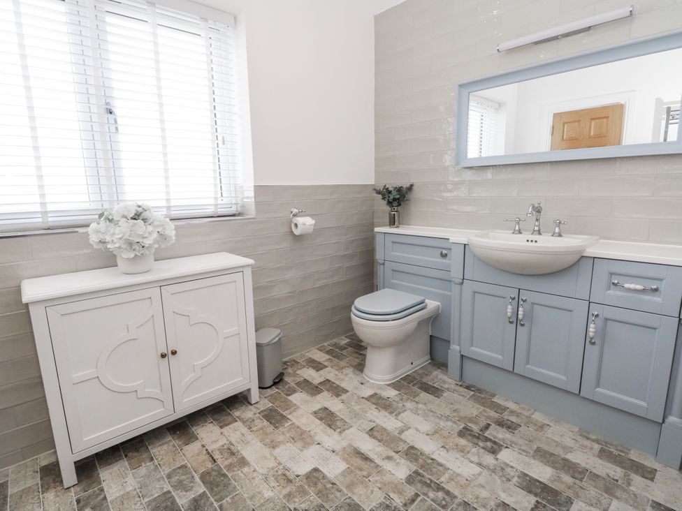 A bathroom with a sink, toilet, and cabinet at Meadow Manor And Spa in Prees near Whitchurch