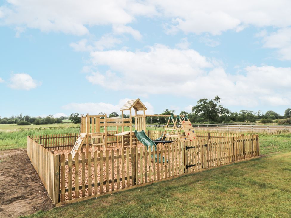A playground with a slide and swings at Meadow Manor And Spa in Prees near Whitchurch
