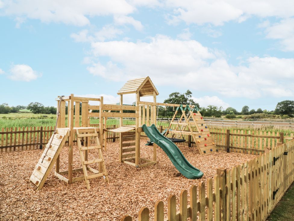 A playground with a slide, swing, and climbing frame at Meadow Manor And Spa near Prees near Whitchurch