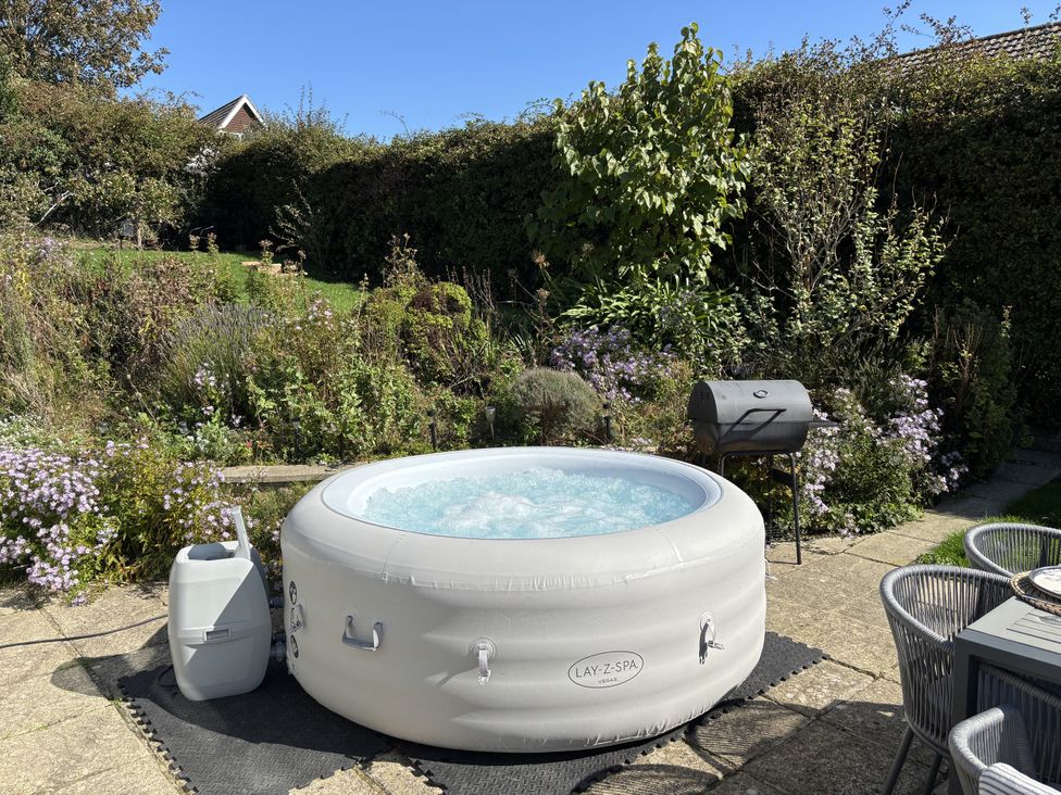 A hot tub and grill in a garden at Topsails Totland Bay