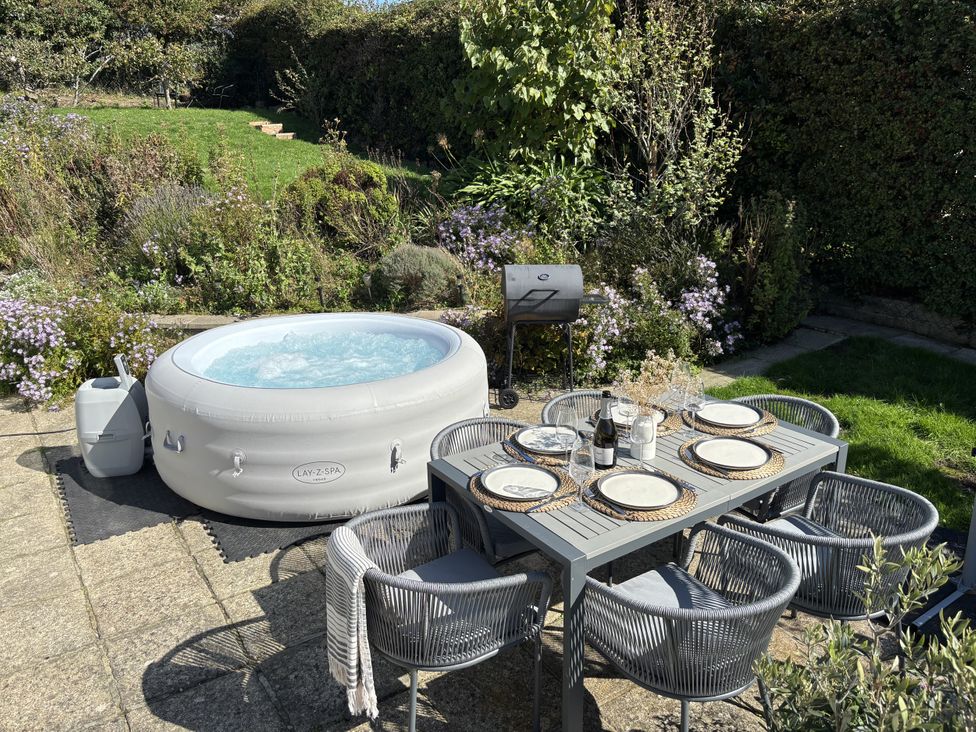A garden with a hot tub and dining setup at Topsails in Totland Bay