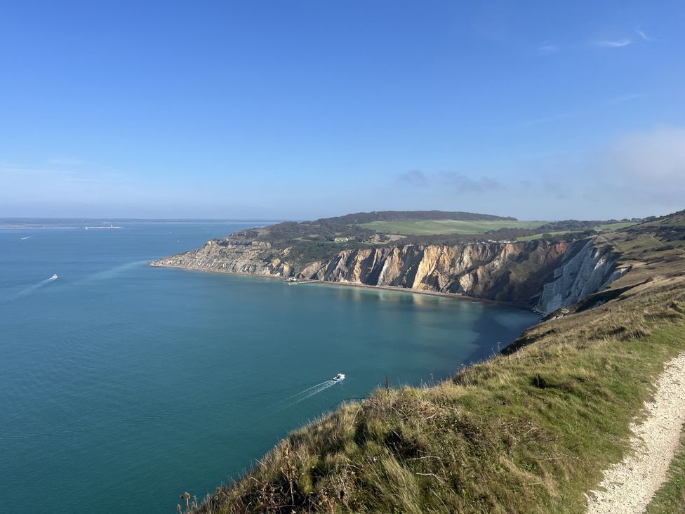 A coastal view with cliffs and a boat in the ocean at Topsails in Totland Bay