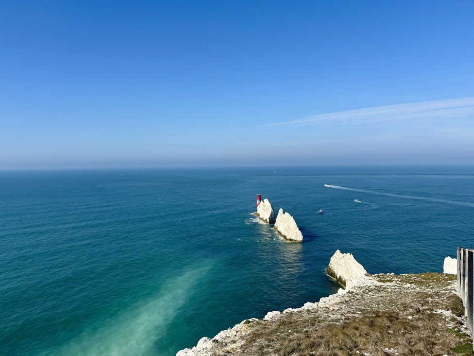 An ocean view with a lighthouse on rocks and boats at Topsails in Totland Bay