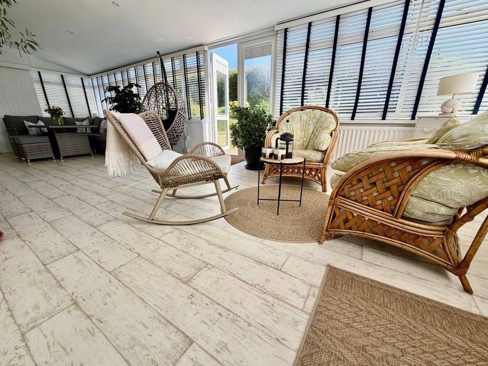 A conservatory with seating and plants at Topsails in Totland Bay