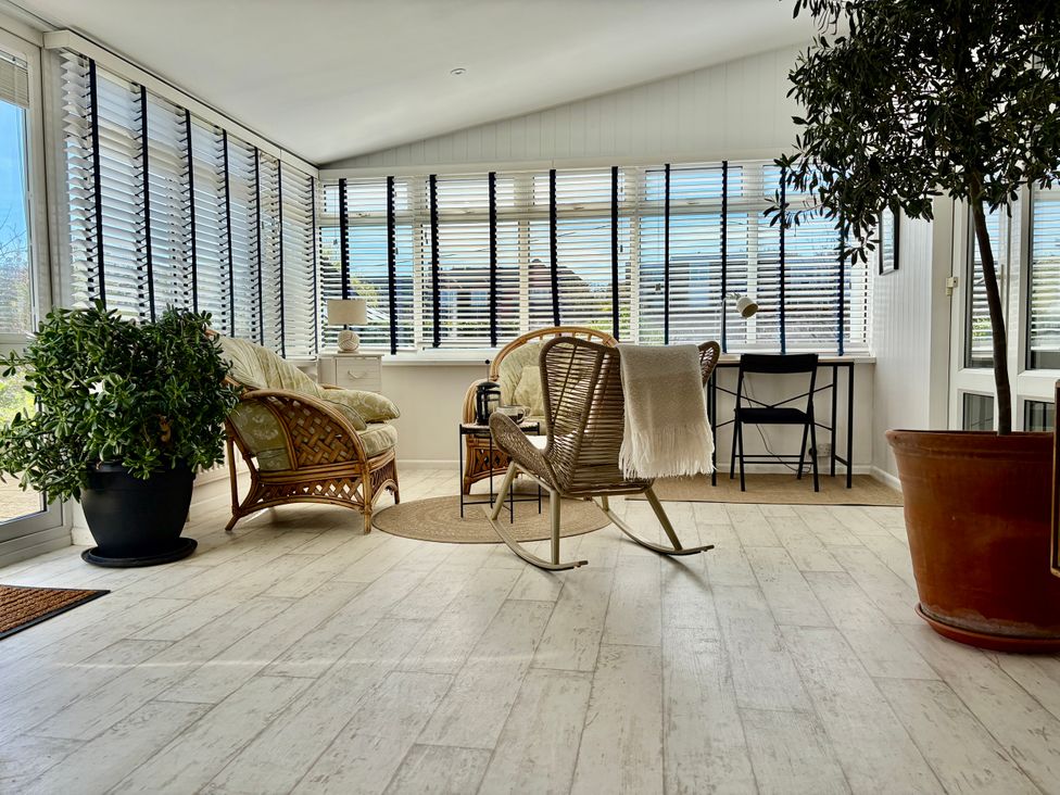 A conservatory with seating and a table at Topsails in Totland Bay