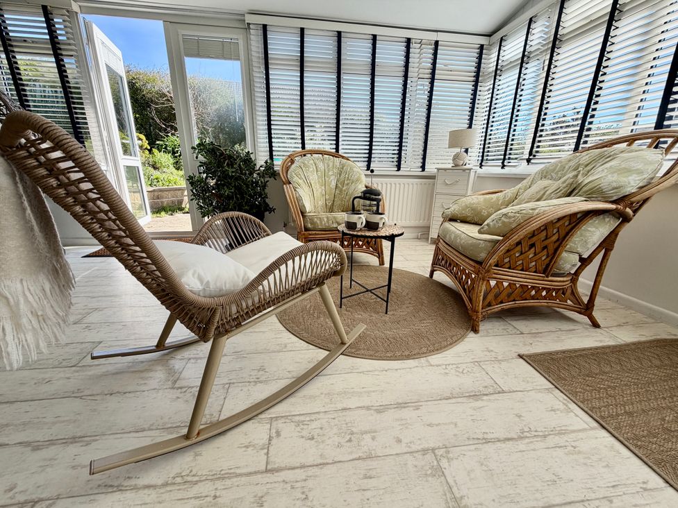 A conservatory with chairs and a table at Topsails in Totland Bay