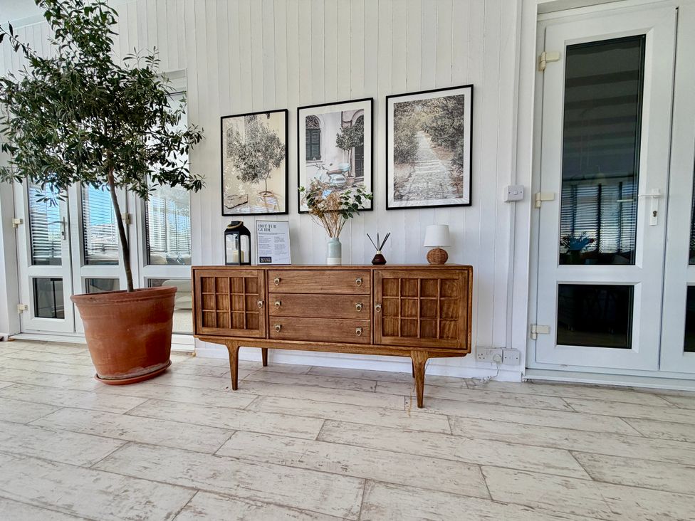 A wooden cabinet with photo frames and a plant at Topsails in Totland Bay