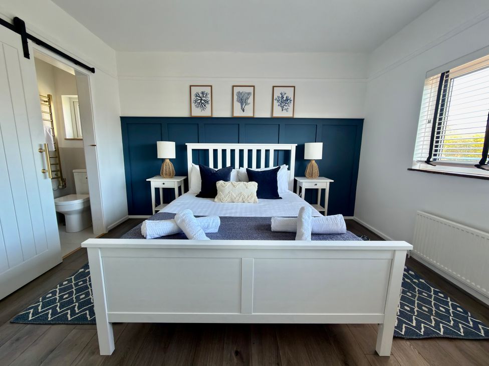 A bedroom with a bed and bedside tables at Topsails in Totland Bay