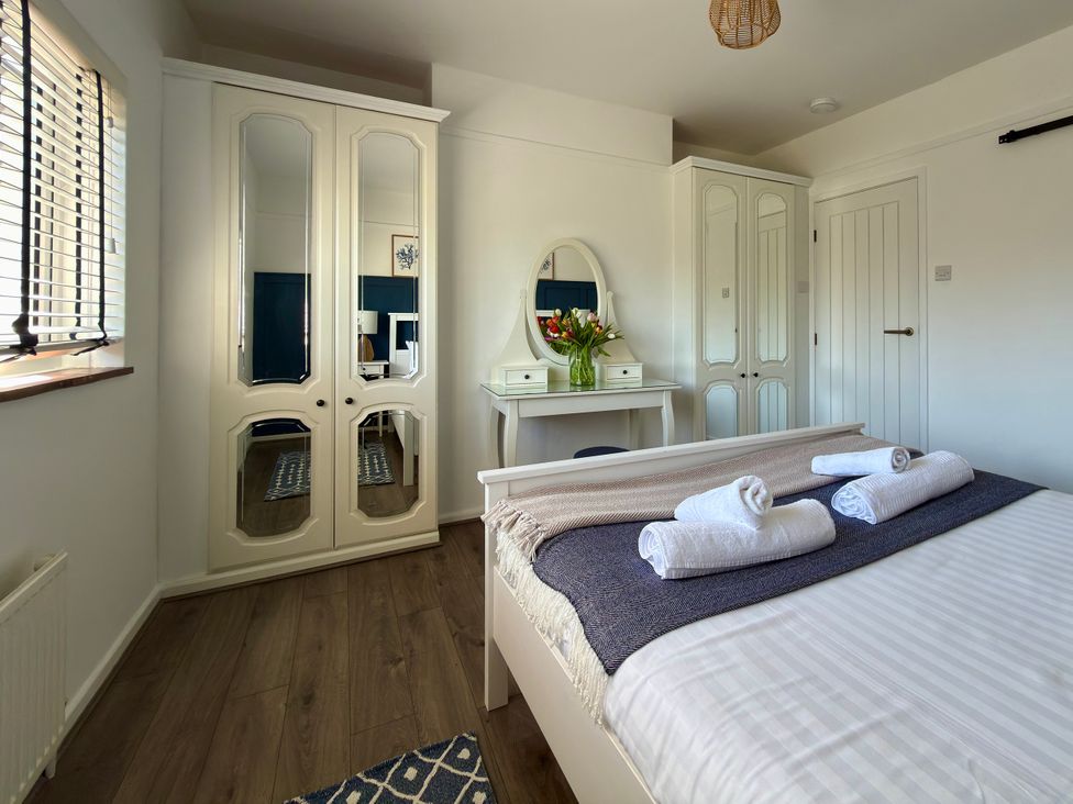 A bedroom with a bed and wardrobe at Topsails in Totland Bay