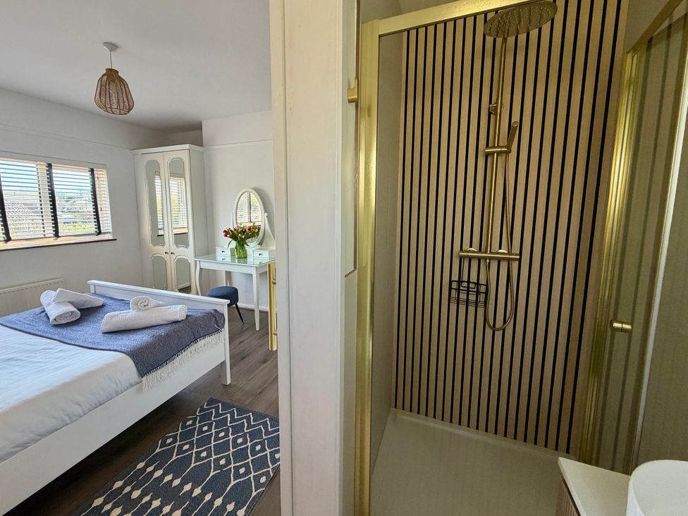 A bedroom with a bed and a shower room at Topsails in Totland Bay