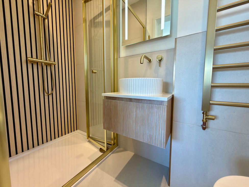 A bathroom with a shower, sink and towel rail at Topsails in Totland Bay