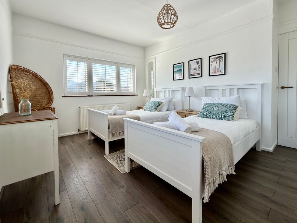 A bedroom with two beds and a nightstand at Topsails in Totland Bay