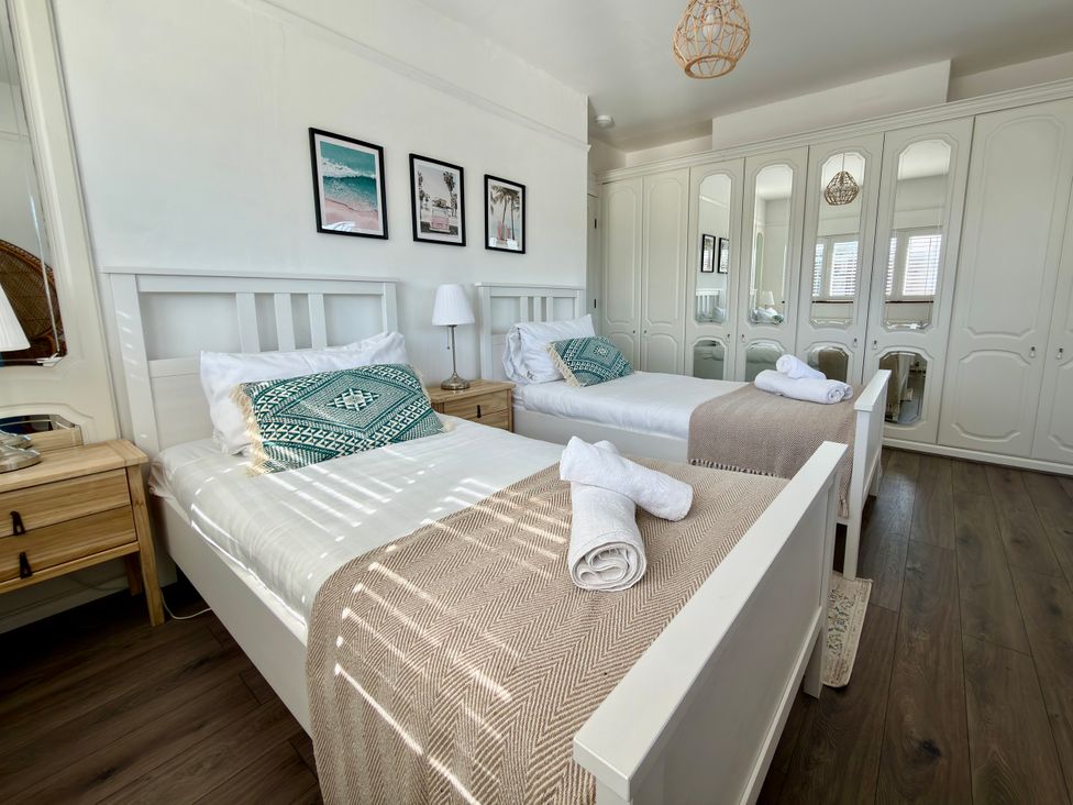A bedroom with two beds and a wardrobe at Topsails in Totland Bay