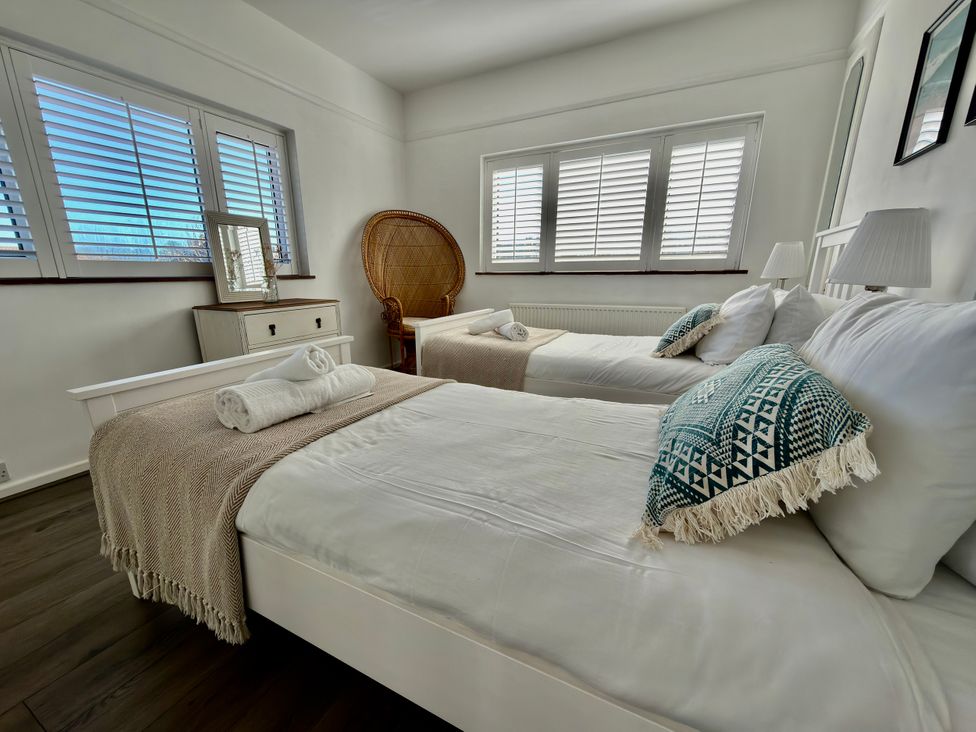 A bedroom with two beds and a chair at Topsails in Totland Bay