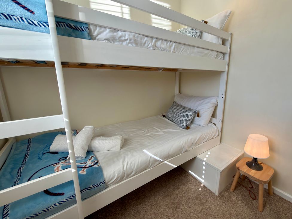 A bedroom with a bunk bed and bedside table at Topsails in Totland Bay