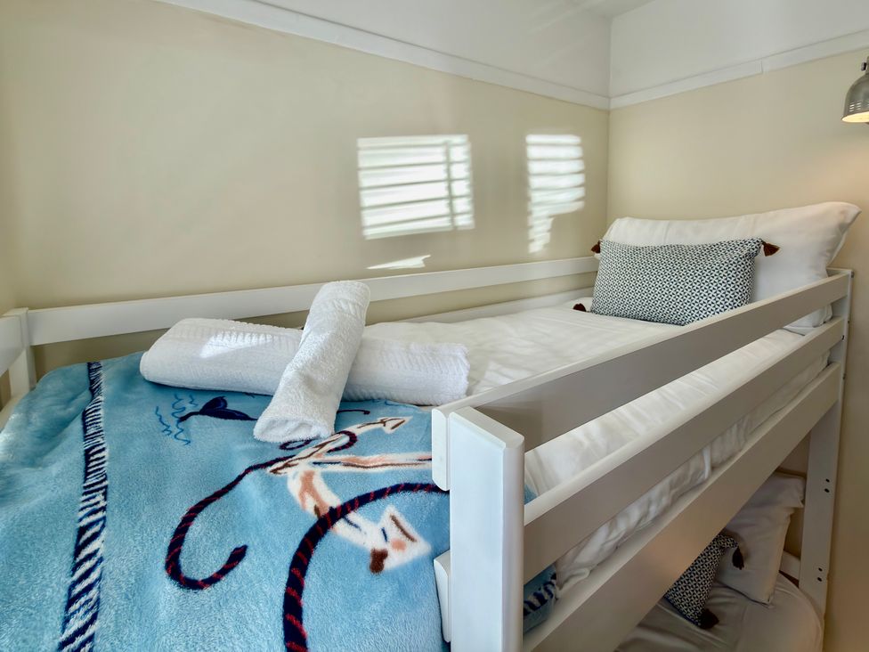 A bed with a blue blanket and pillows at Topsails in Totland Bay