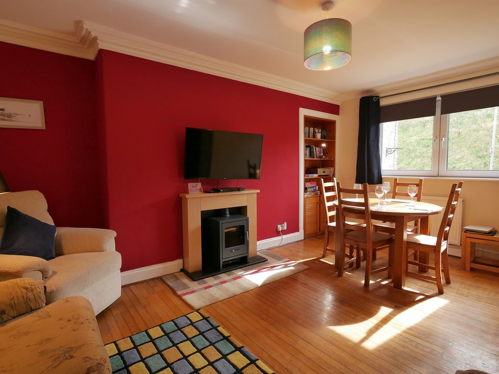 A living room with a fireplace and dining table at Seal Cottage in Eyemouth