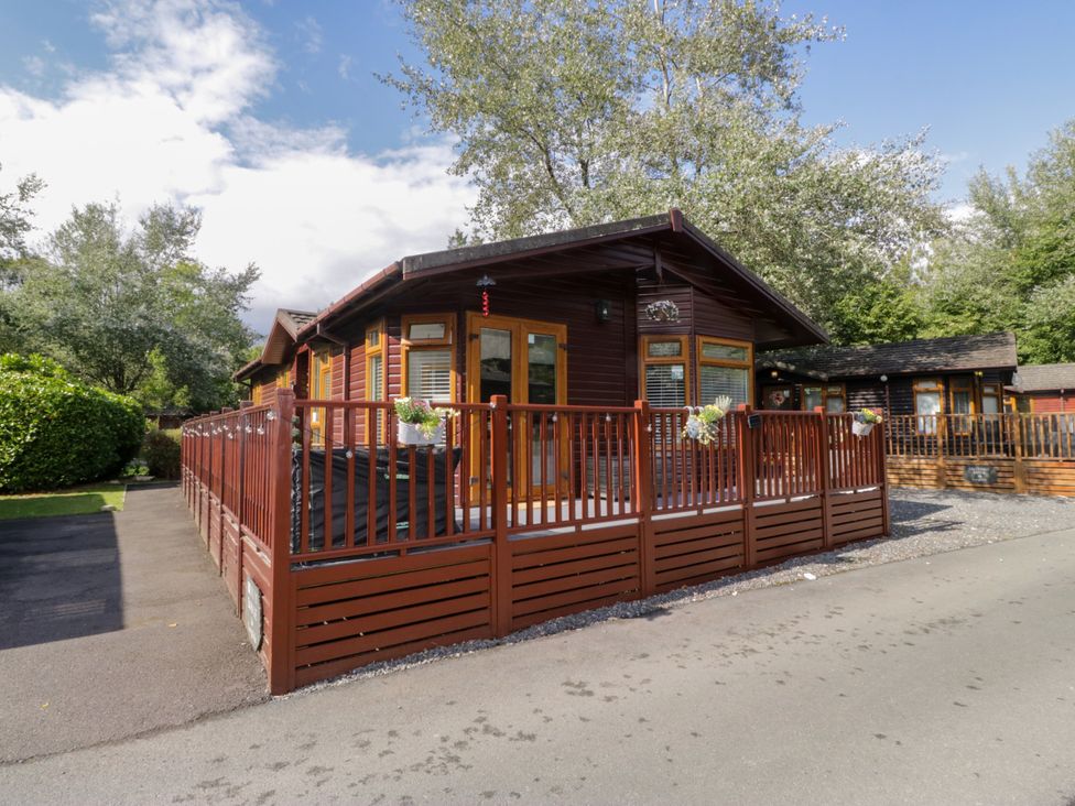 A lodge with a wooden deck and fence at Ruskin Lodge, Langdale 16, White Cross Bay near Windermere