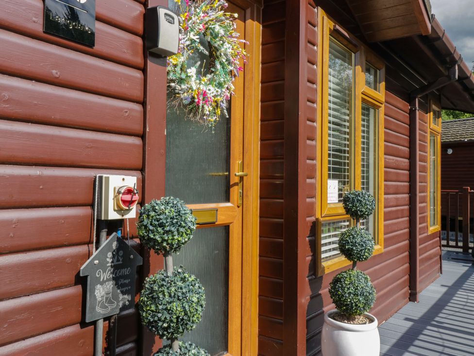 An entrance with a welcome sign and topiary plants at Ruskin Lodge, Langdale 16, White Cross Bay near Windermere