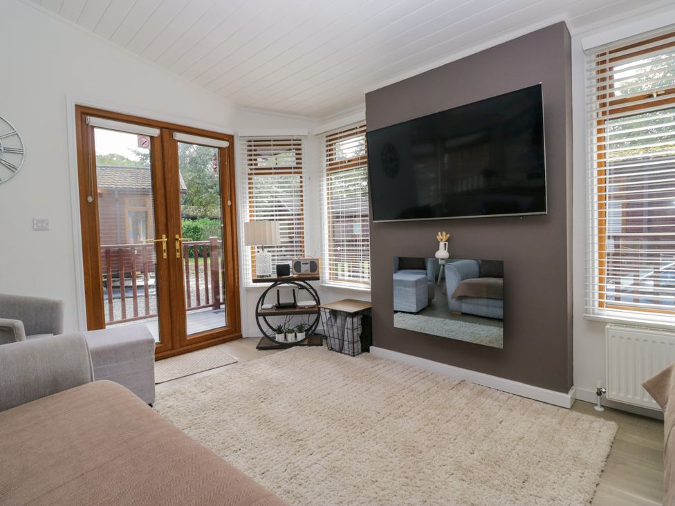 A living room with a television and sofa at Ruskin Lodge Langdale 16, White Cross Bay near Windermere