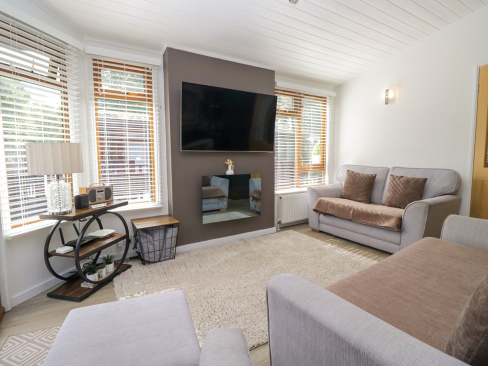 A living room with a television mounted on the wall at Ruskin Lodge, Langdale 16, White Cross Bay near Windermere