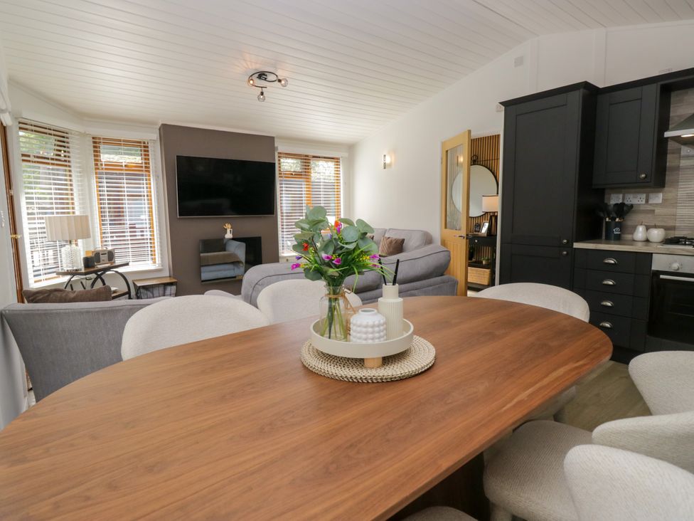 A living room with a sofa, table, and television at Ruskin Lodge, Langdale 16, White Cross Bay near Windermere