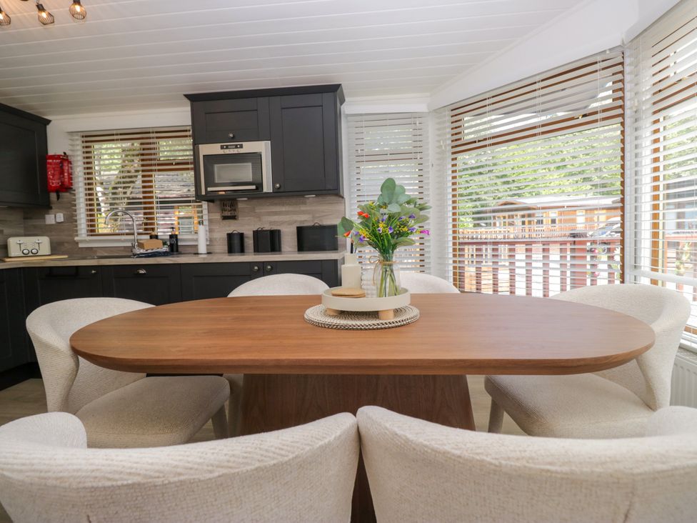 A dining room with a round table and chairs at Ruskin Lodge, Langdale 16, White Cross Bay near Windermere