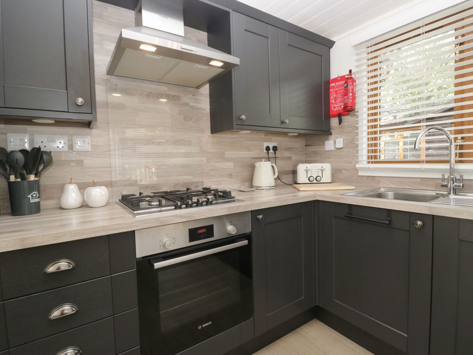 A kitchen with a stove and sink at Ruskin Lodge Langdale 16, White Cross Bay near Windermere