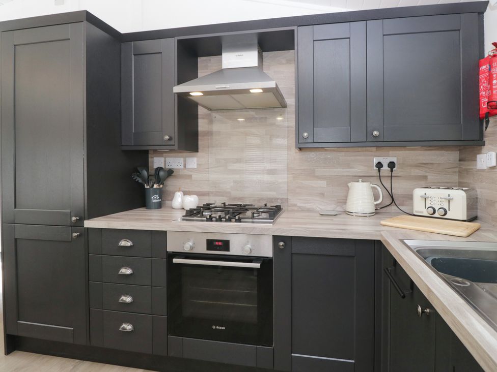 A kitchen with appliances and cabinets at Ruskin Lodge Langdale 16, White Cross Bay near Windermere